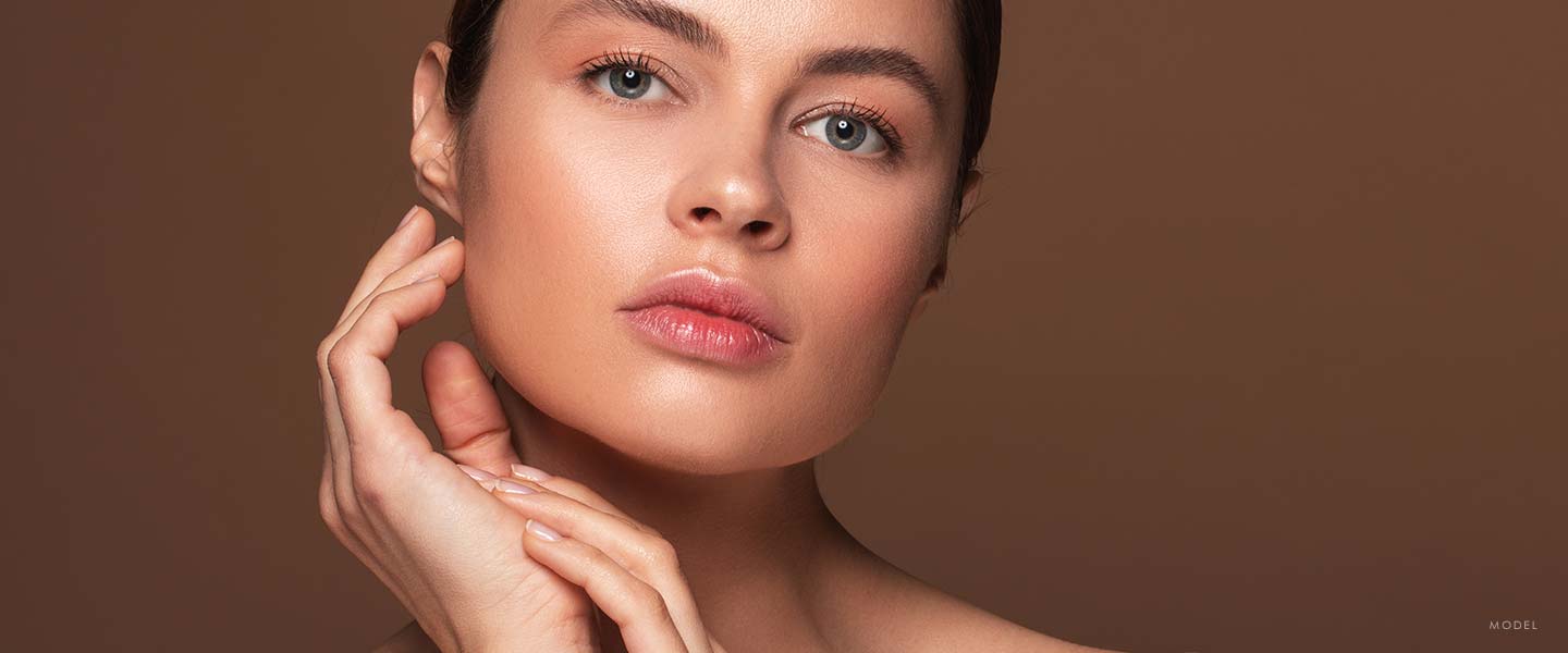 Headshot of a woman caressing her smooth face