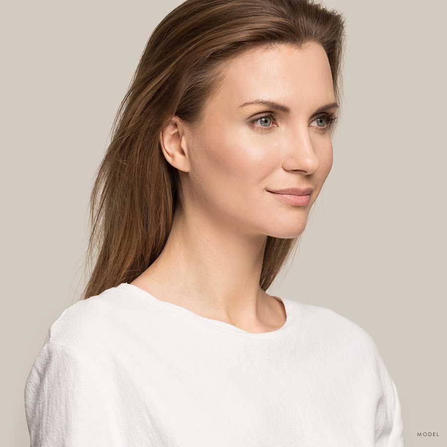 Sideview headshot of a brunette woman in a white loose blouse