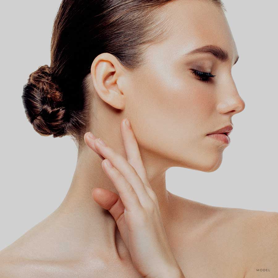 Sideview headshot of a female model brushing her hand on her neck