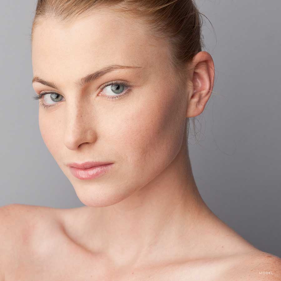 Headshot of a young woman with clear skin and bare shoulders