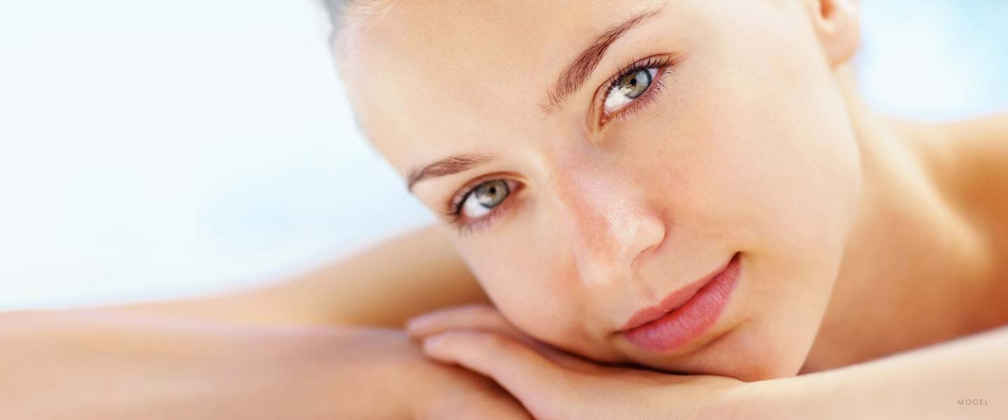 Headshot of a woman resting her face in her arms