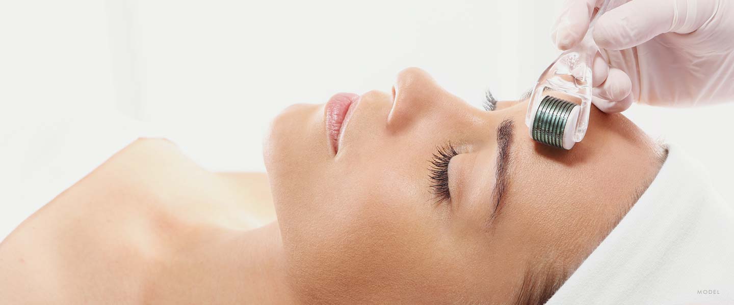 Headshot of a woman in a towel laying in a spa bed getting treatment applied her forehead