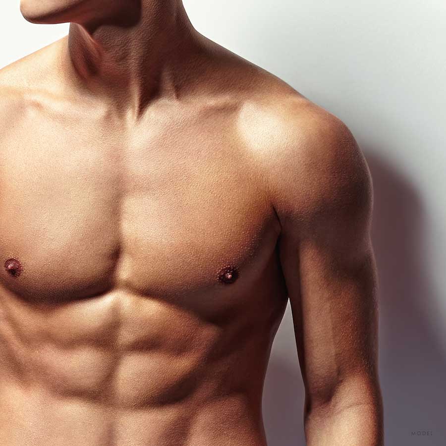 Mid body shot of a male model with a sculpted and fit chest and abs